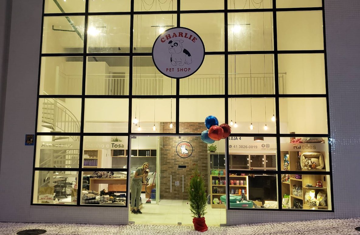 Fachada iluminada da loja Charlie Pet Shop e Estética Animal, com a logo redonda em destaque.